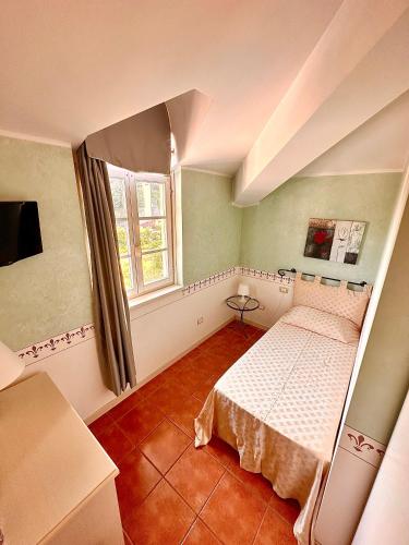 a small bedroom with a bed and a window at Caroline Hotel in Brusimpiano