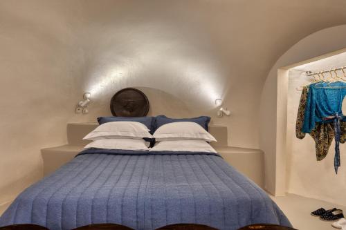 una camera da letto con letto blu e cuscini bianchi di Kore Cave House by Oias Local Cave Houses a Oia
