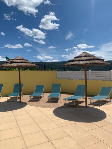 a group of chairs and umbrellas on a patio at Aux couleurs d’Ardèche in Vallon-Pont-dʼArc