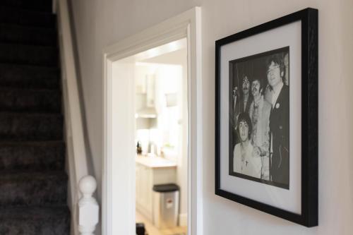 a framed picture of a group of people on a wall at Modern & Stylish Home at the corner of famous Penny Lane in Liverpool in Liverpool