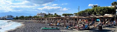 a beach with many chairs and umbrellas and people at Villa Komorebi in Ierápetra