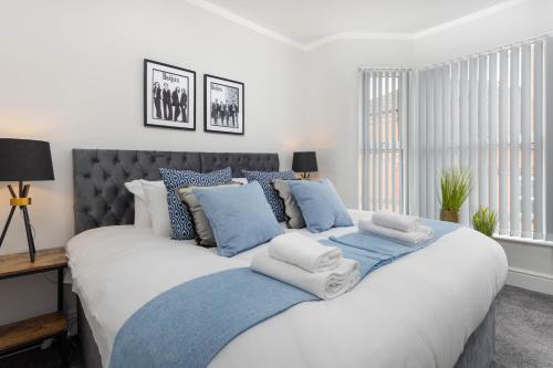 um quarto com uma cama grande e almofadas azuis e brancas em Stylish & modern home across the road from the famous Penny Lane walking distance to cafes restaurants and supermarkets em Liverpool