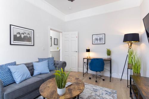 ein Wohnzimmer mit einem Sofa und einem Tisch in der Unterkunft Stylish & modern home across the road from the famous Penny Lane walking distance to cafes restaurants and supermarkets in Liverpool