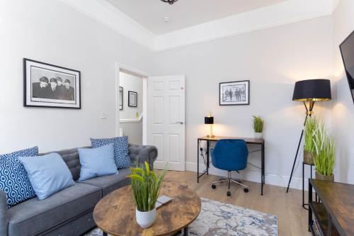a living room with a couch and a table at Stylish & modern home across the road from the famous Penny Lane walking distance to cafes restaurants and supermarkets in Liverpool