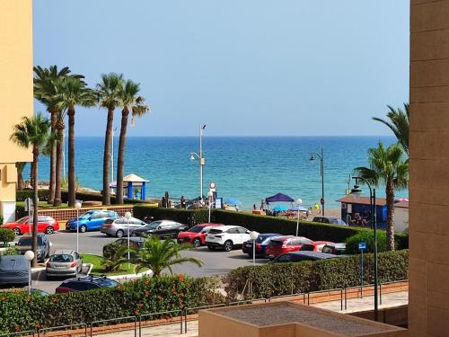 Casa Playa Guadalmar في مالقة: موقف للسيارات مع أشجار النخيل والمحيط