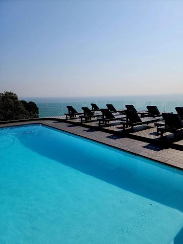 una piscina con sillas y vistas al océano en Bikini Beach Manor, en Gordonʼs Bay