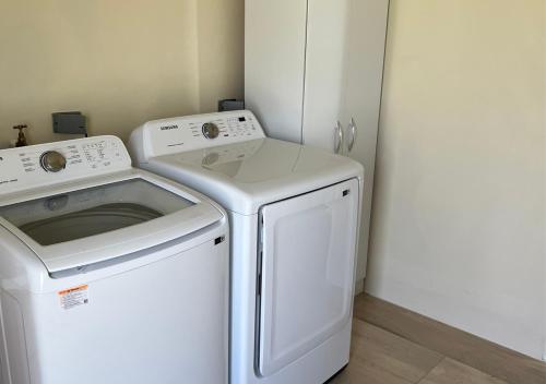 Lavadora y secadora blancas en una habitación pequeña en Caspian Villa, en Arima