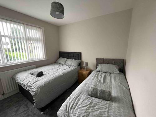 a bedroom with two beds and two windows at Modern Family home large garden free parking in Newcastle upon Tyne