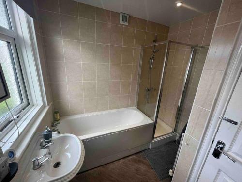 a bathroom with a shower and a tub and a sink at Modern Family home large garden free parking in Newcastle upon Tyne
