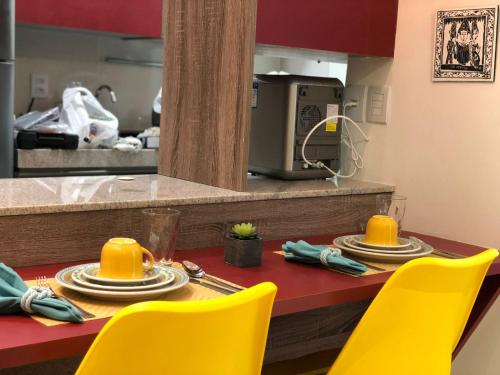a dining room table with yellow chairs and a kitchen at Flat Versatti - Próximo Real Hospital Port e Pólo Médico Ilha do Leite in Recife