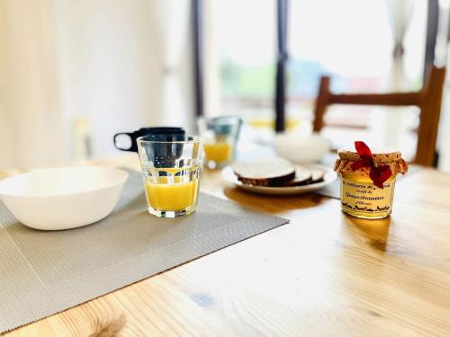 une table en bois avec un verre de jus d'orange et de nourriture dans l'établissement Le Studio Bleu*10' centre*Parking*Balcon, à Colmar