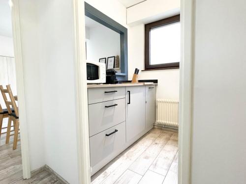 une cuisine avec des armoires blanches et un micro-ondes dans l'établissement Le Studio Bleu*10' centre*Parking*Balcon, à Colmar