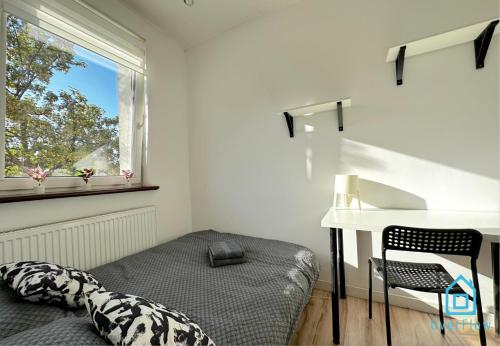 Schlafzimmer mit einem Bett, einem Schreibtisch und einem Fenster in der Unterkunft Sobieski Room in Danzig