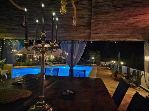 a dining room with a table and a pool at night at Finca la Yuca in Ontinyent