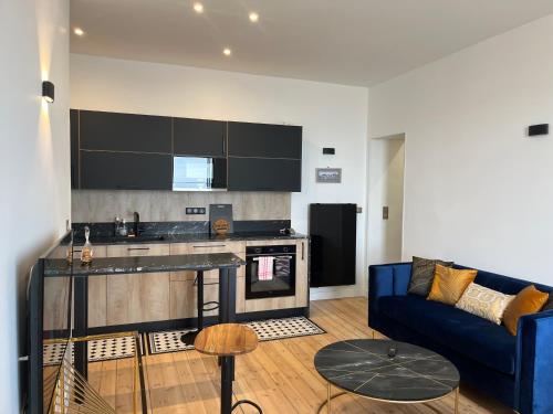 ein Wohnzimmer mit einem blauen Sofa und einer Küche in der Unterkunft Le Royal XIX Dinard vue mer luxe in Dinard