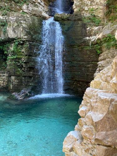 a waterfall with a pool of water in front of a rock wall at Villa Meta - Welcoming You with Byrek & Traditional Meals in Gusmar