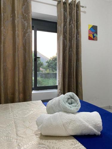 a pile of towels on a bed with a window at Villa Meta - Welcoming You with Byrek & Traditional Meals in Gusmar
