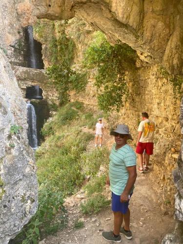a man in a hat standing in front of a waterfall at Villa Meta - Welcoming You with Byrek & Traditional Meals in Gusmar