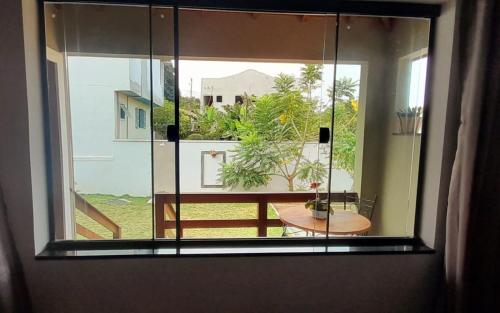 a window with a view of a patio with a table at Sonia Flats - Chalé a 500 metros da Praia da Tartaruga in Búzios