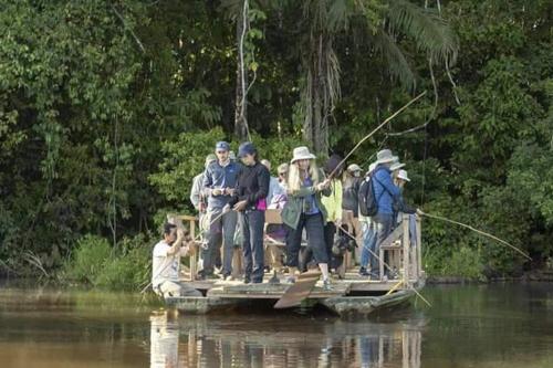 un grupo de personas de pie en una balsa en el agua en Tambopata Edosikiana Lodge en Tambopata