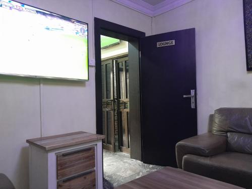 MITOS LUXURY SUITES (ANNEX) في لاغوس: غرفة معيشة مع أريكة و شاشة عرض