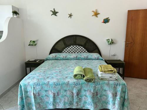 Schlafzimmer mit einem Bett mit blauer Decke in der Unterkunft Il monolocale verde conchiglie e fiori in Ponza