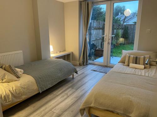 1 dormitorio con 2 camas y puerta corredera de cristal en Cornwall Tranquil Retreats, en Saltash