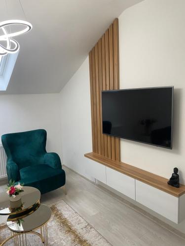 a living room with a blue chair and a flat screen tv at Legato Apartment in Brčko