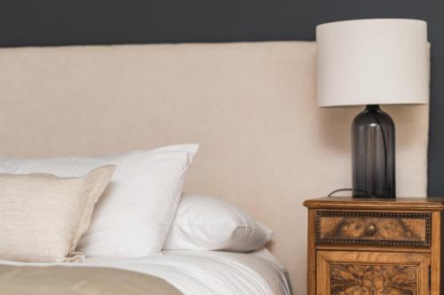 a bed with white pillows and a lamp on a night stand at Bories - Boutique Guest House in Puerto Natales