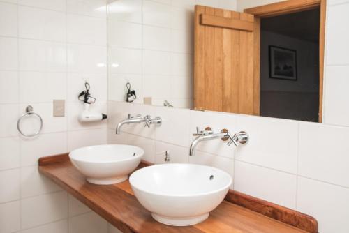 a bathroom with two white sinks on a wooden counter at Bories - Boutique Guest House in Puerto Natales