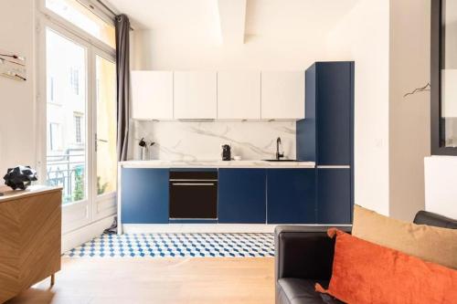 a kitchen with blue and white cabinets and a couch at Studio standing plein centre Aix in Aix-en-Provence