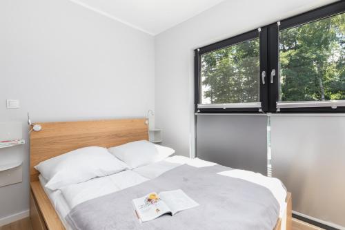 a bedroom with a bed and two windows at Apartament Baltic&SPA - Aprent in Międzywodzie