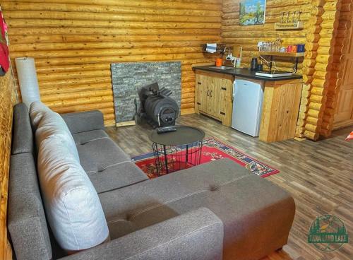 a living room with a couch and a kitchen in a log cabin at Tara Land Lake in Zaovine