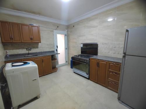 a kitchen with wooden cabinets and a stove and a refrigerator at الداون تاون العالمين الجديدة خلف الابراج_ElDown Town New alameim in El Alamein