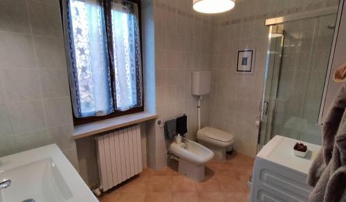 a bathroom with a toilet and a tub and a sink at Casa Il Volo in San Zeno di Montagna