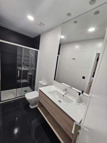 a bathroom with a sink and a toilet and a mirror at Brand new Port Relax with AC by Santiago in San Sebastián