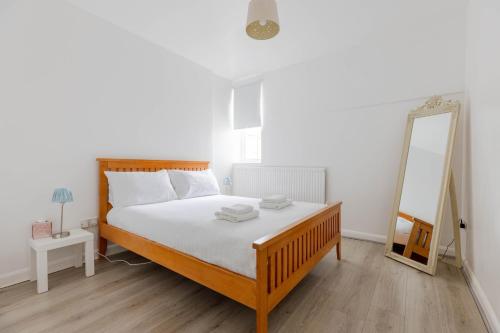 a bedroom with a large bed and a mirror at Cosy 2 bedroom apartment near WEMBLEY, garden, late check in in London