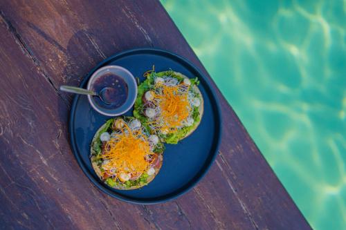 a blue plate of food on a table next to a pool at XscapeTulum in Tulum