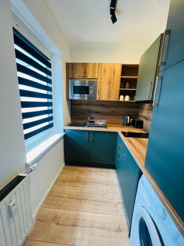 a kitchen with blue cabinets and a window at Sofia Apartment & Zimmer Nähe Redbull Ring in Knittelfeld