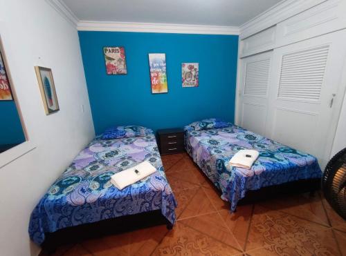 two beds in a room with blue walls at Hospedaje Casa Aurora in Cali