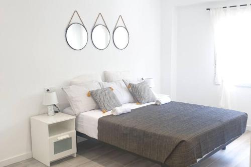 - une chambre blanche avec un lit et deux miroirs sur le mur dans l'établissement Elda, Alicante, à Elda