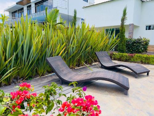 two wicker chairs and flowers on a patio at Lago Calima Bliss: Secret Garden Paradise in Darien in Darién