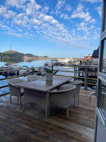a table and chairs on a deck with a marina at Autentisk rorbu in Moskenes