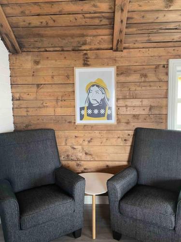 two chairs and a table in a room with wooden walls at Autentisk rorbu in Moskenes