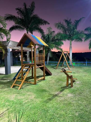a group of playground equipment in a park with palm trees at Lindo Apartamento no Condomínio Alto da Serra Villas de Bananeiras in Bananeiras