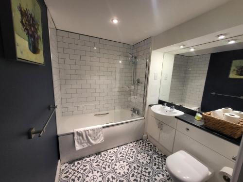a bathroom with a tub and a sink and a toilet at Excel Manor in London