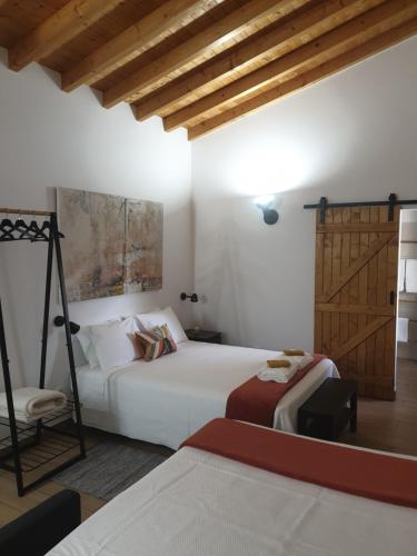 a bedroom with two beds and a wooden door at Casa das Almoleias in Castro Verde