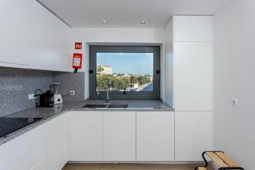 a kitchen with white cabinets and a window at Romantic Pool House in Vila do Conde
