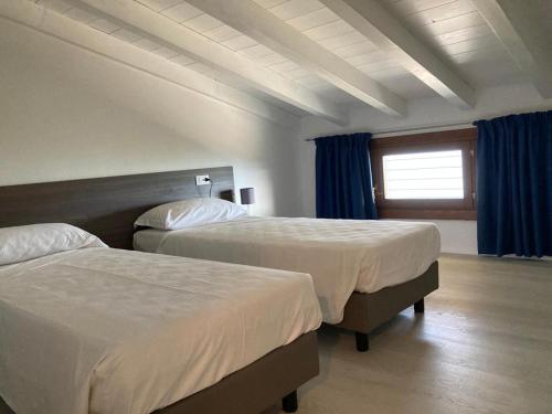 una camera d'albergo con due letti e una finestra di La Casa sul Lago Apartments - Blue Wave Apartment a Limone sul Garda