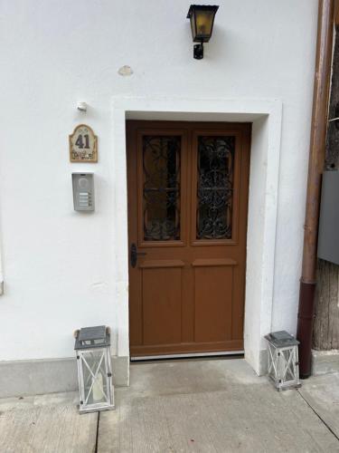 a brown door on a white building with two stools at MARYS family friendly Apartments,VISIT RHINE FALLS for FREE if you stay 2 nights, SOHO 95m2 2-Bedrooms 2nd floor & SOUTH BEACH 105m2 3-Bedrooms & LOFT 115m2 3-Bedrooms Suite with Galerie,LOFT Netz 20m2, Pinball, Schaffhausen-Hemmental, Rheinfall 10 km in Schaffhausen